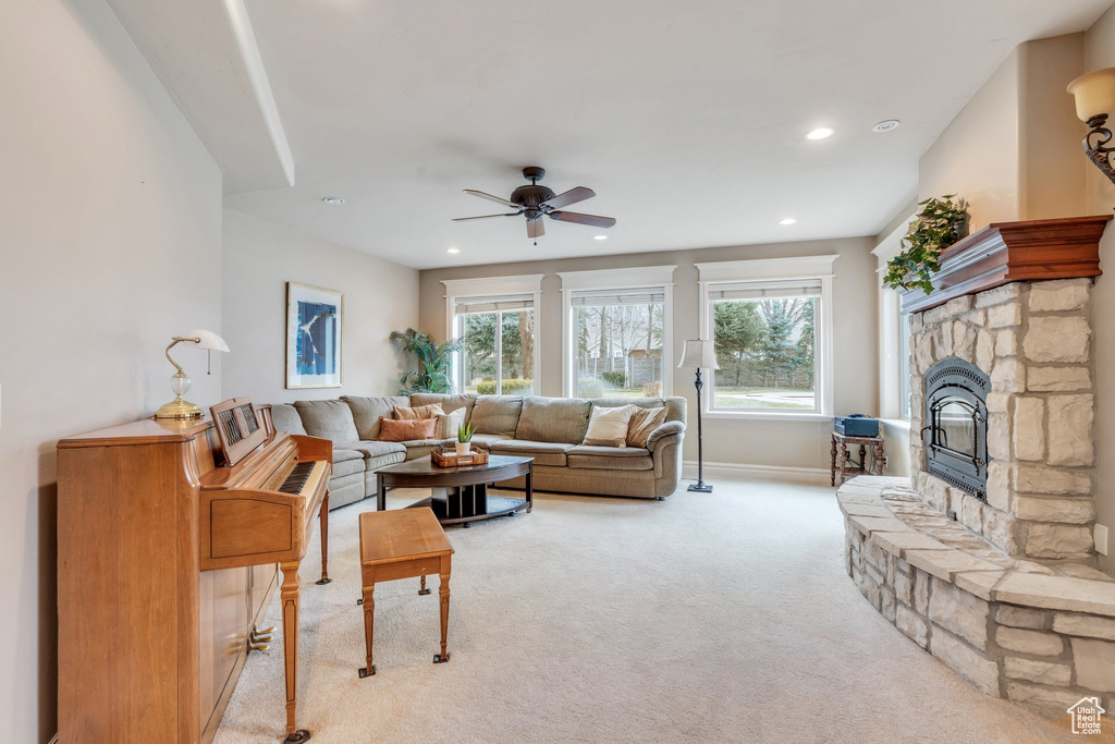 Living area with a fireplace, ceiling fan, a wealth of natural light, and light colored carpet