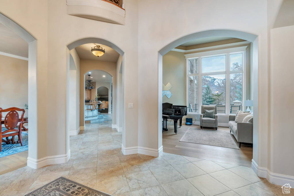 Corridor with a high ceiling, light wood-style floors, arched walkways, and baseboards