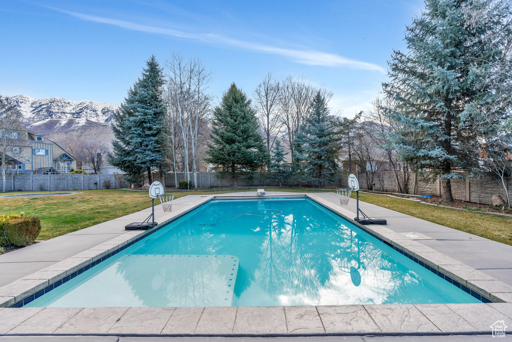 View of swimming pool with a fenced in pool, a fenced backyard, a mountain view, a yard, and a patio area