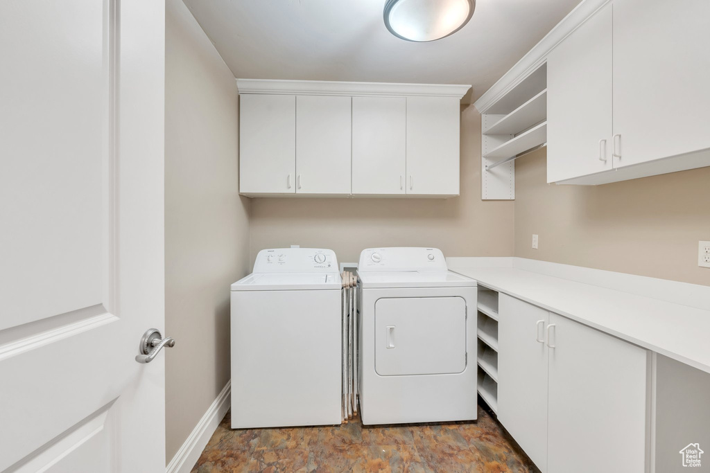 Laundry area featuring cabinet space, baseboards, washer and clothes dryer, and stone finish floor