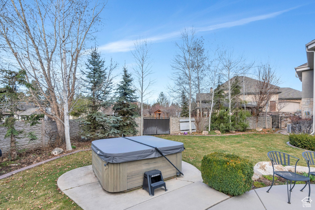 View of yard with a hot tub, fence, and a patio