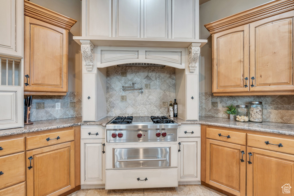 Kitchen featuring stainless steel gas cooktop, backsplash, and light stone counters