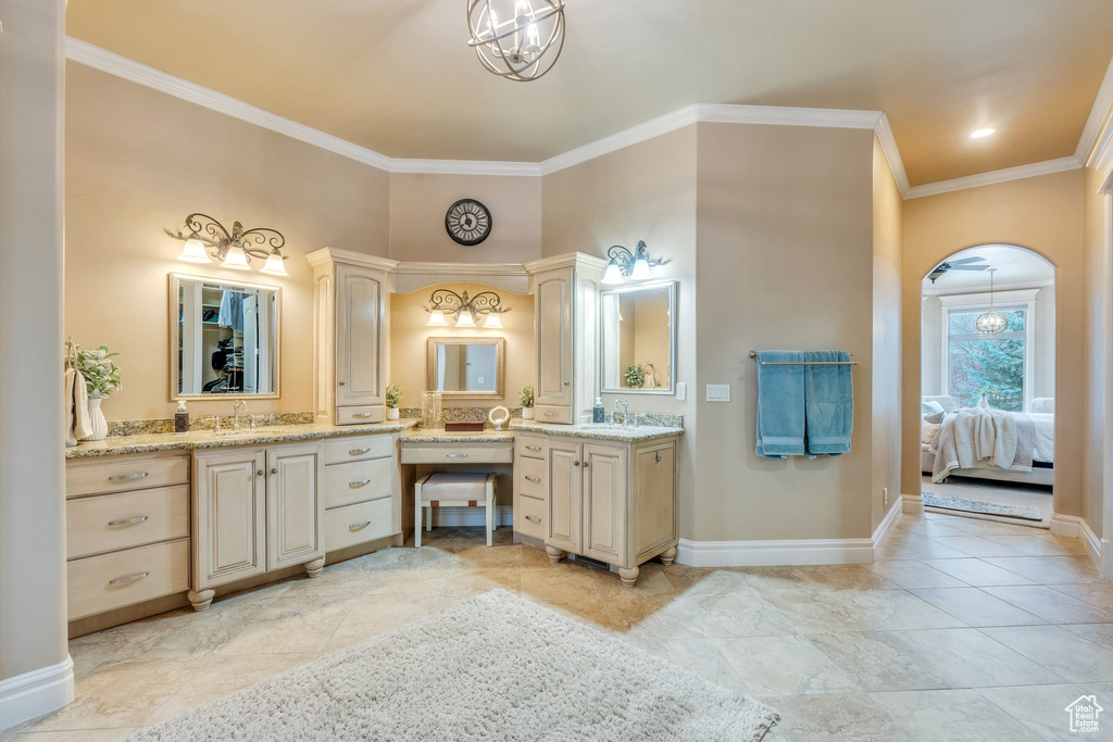 Ensuite bathroom featuring an inviting chandelier, connected bathroom, baseboards, and crown molding