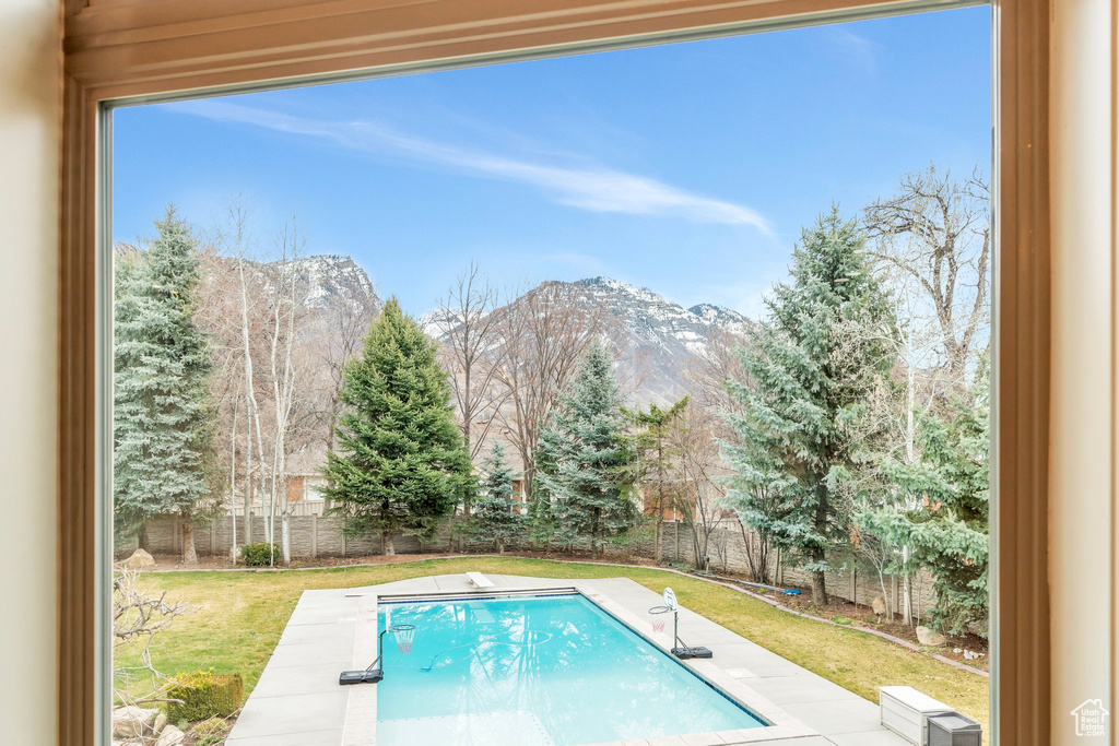 View of swimming pool with a diving board, a fenced in pool, and a mountain view