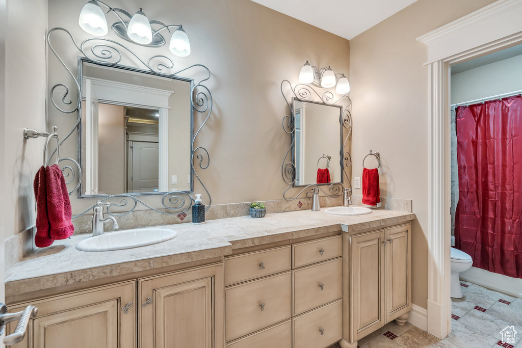 Full bathroom featuring double vanity, a sink, toilet, and curtained shower