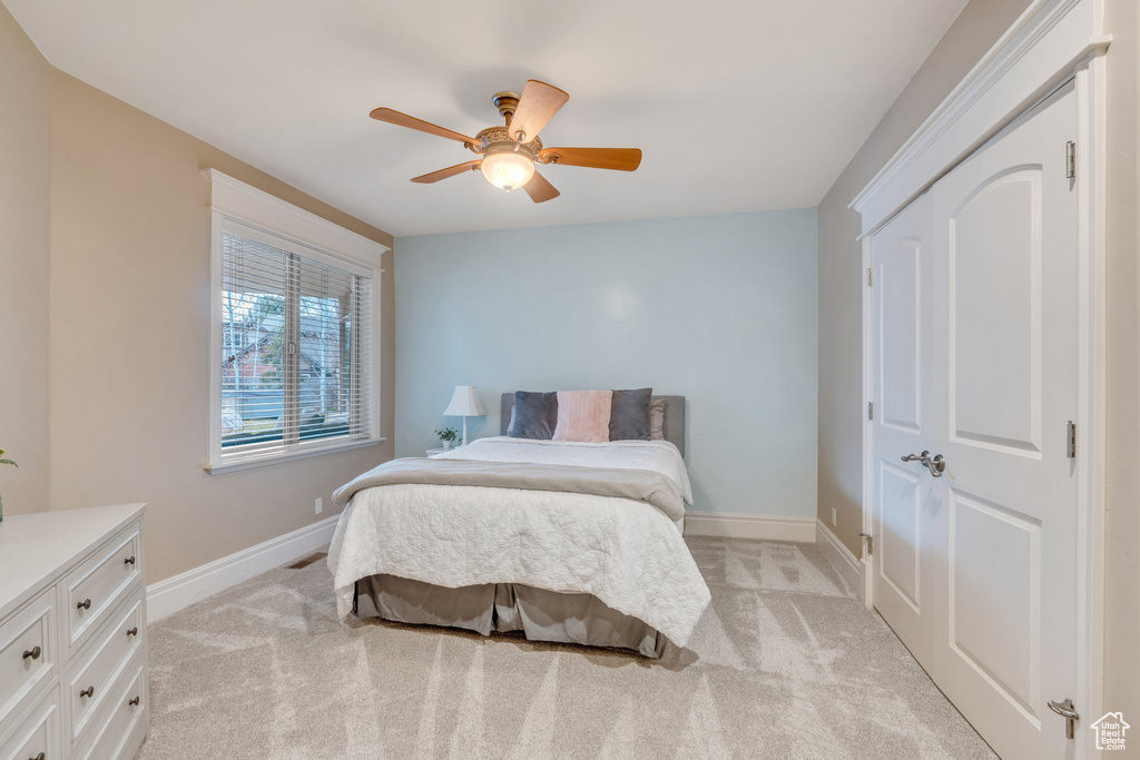 Bedroom featuring baseboards, a ceiling fan, and light carpet