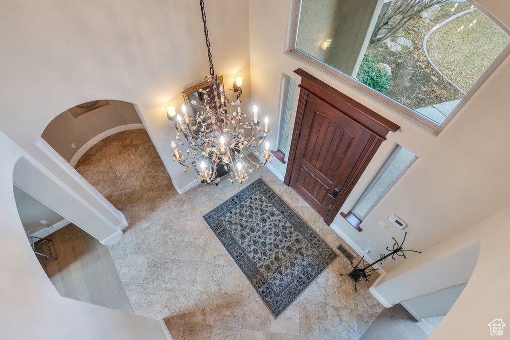 Entryway with a high ceiling, arched walkways, a chandelier, and visible vents