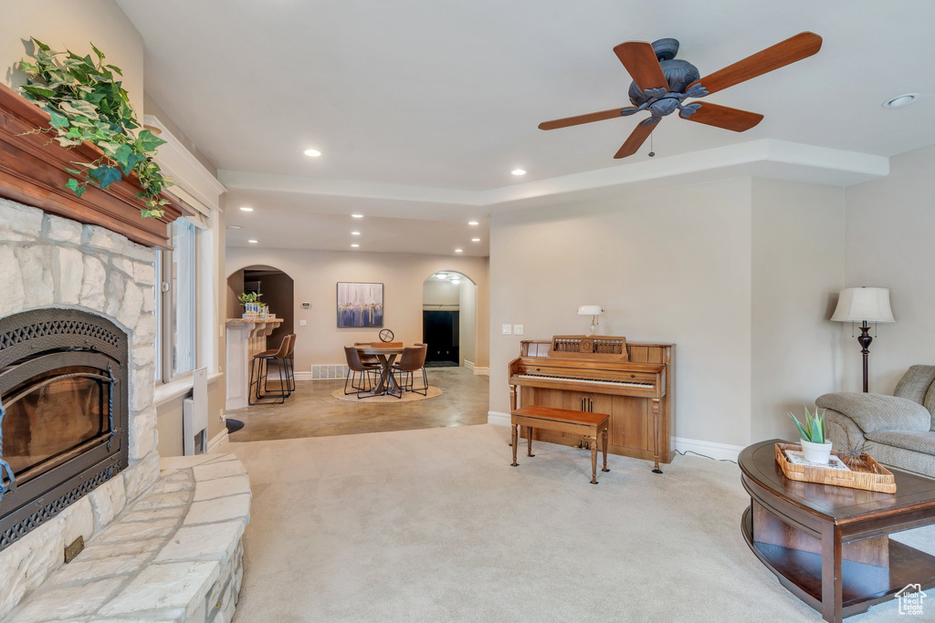 Living room with light carpet, a fireplace, arched walkways, ceiling fan, and recessed lighting