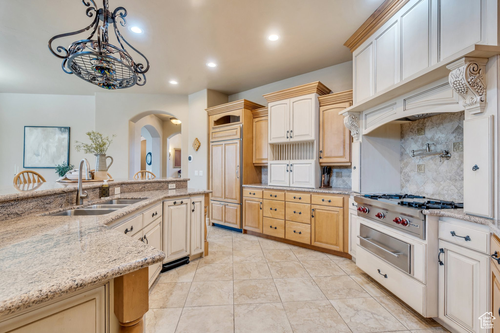 Kitchen with a sink, pendant lighting, stainless steel gas stovetop, arched walkways, and decorative backsplash