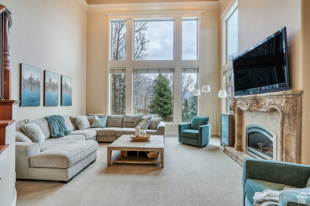 Living room with a high ceiling, ornamental molding, carpet, and a glass covered fireplace