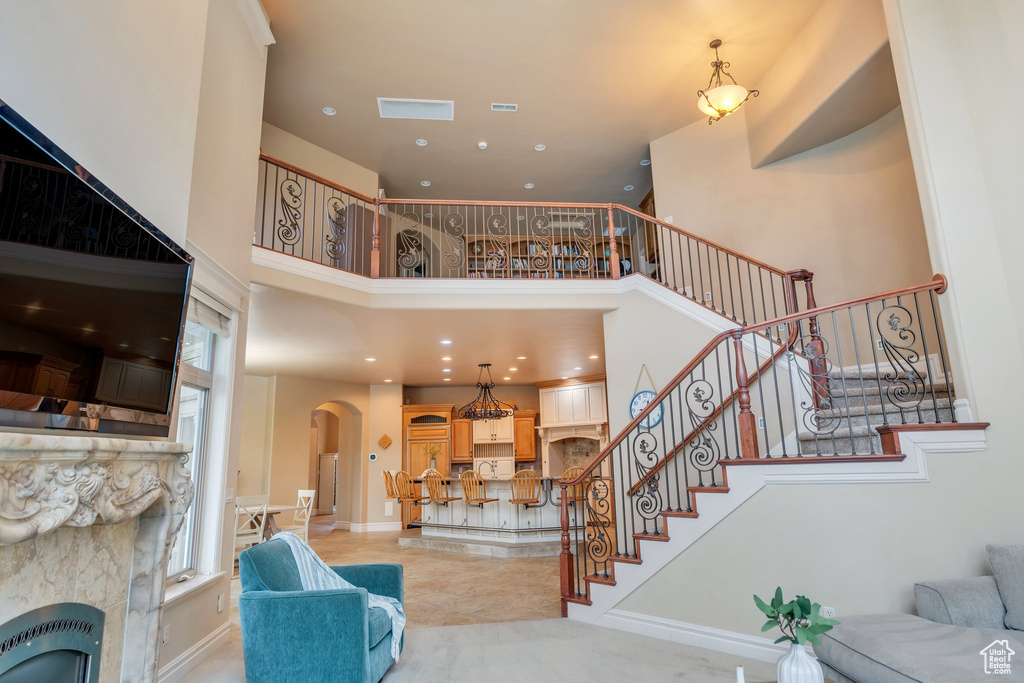 Living area with heating unit, arched walkways, stairway, and a high ceiling