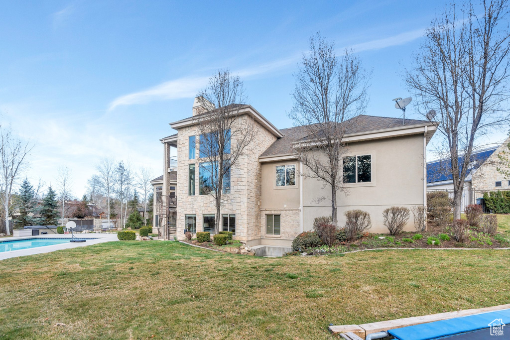 View of side of property with a chimney, stucco siding, a shingled roof, an outdoor pool, and a yard