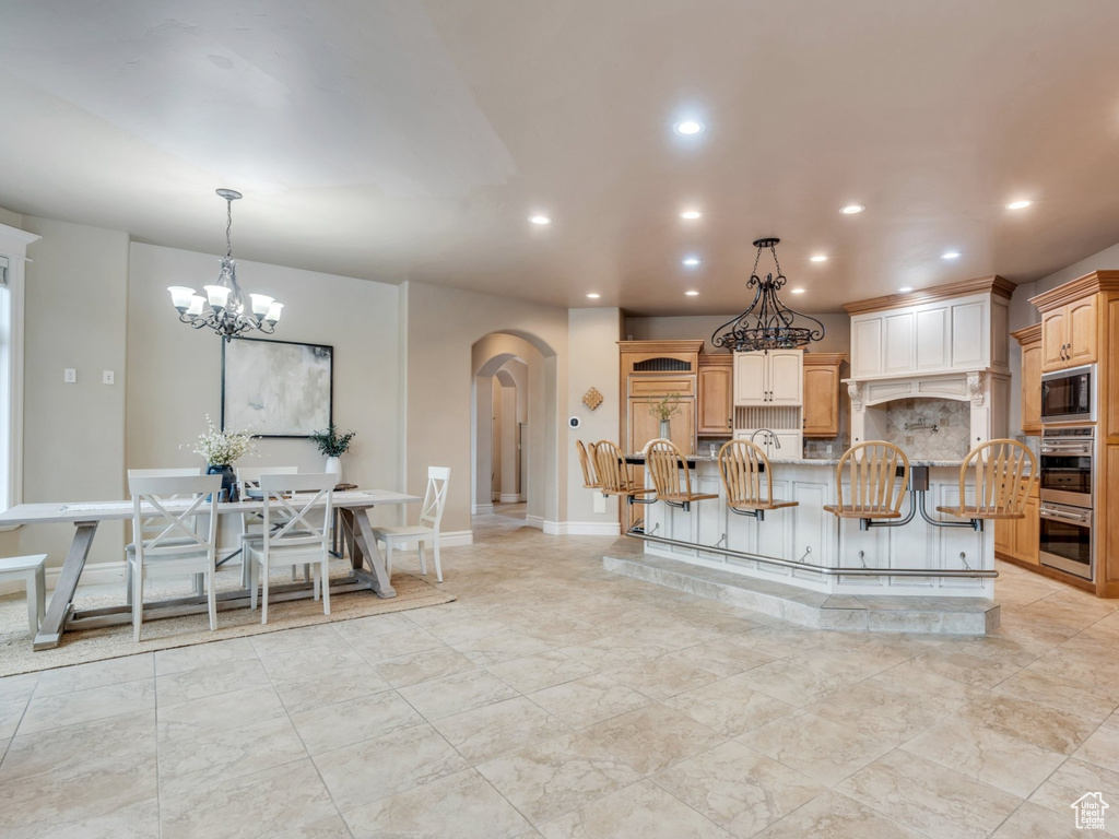Kitchen featuring stainless steel double oven, recessed lighting, tasteful backsplash, arched walkways, and built in microwave