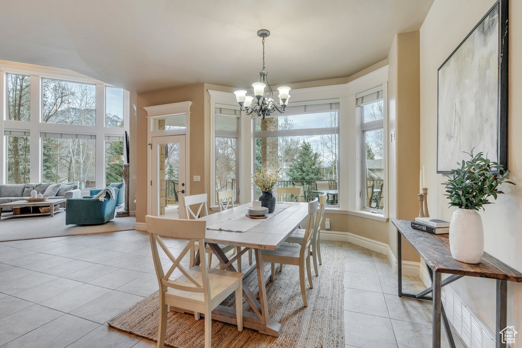 Dining area with light tile patterned floors, a notable chandelier, and baseboards