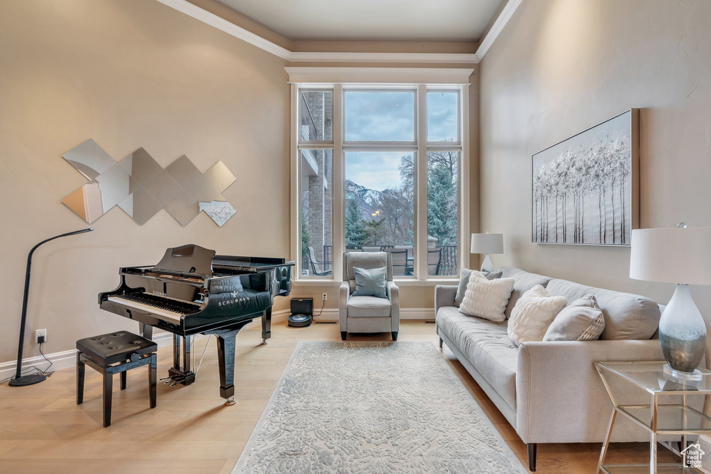 Living area featuring a towering ceiling, ornamental molding, baseboards, and light wood finished floors