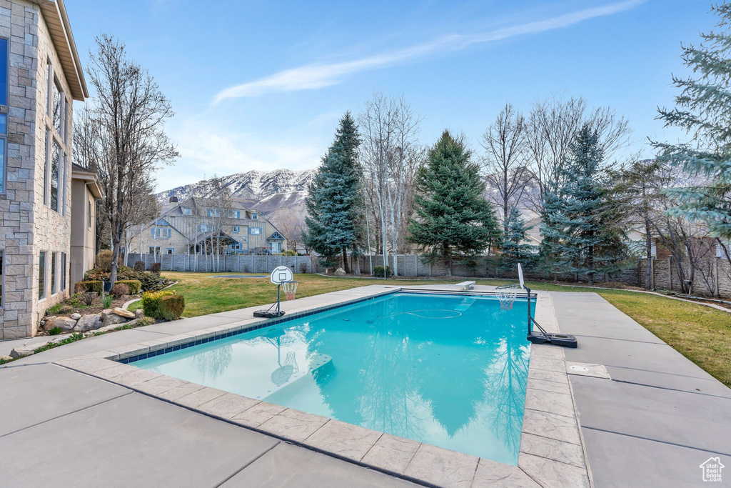 View of swimming pool with a fenced in pool, a fenced backyard, a diving board, a yard, and a patio area