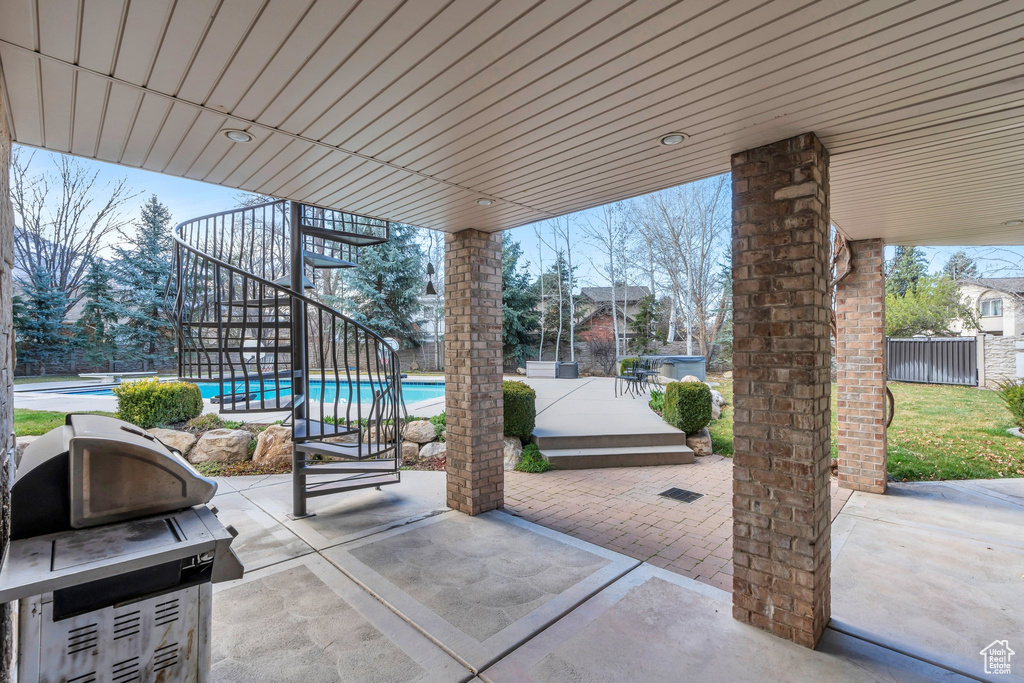 View of patio / terrace with an outdoor pool, area for grilling, fence, and stairs