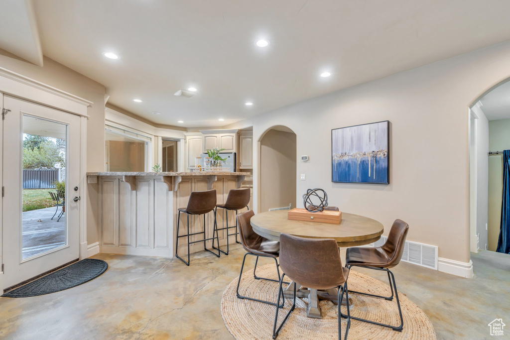 Dining area with visible vents, arched walkways, recessed lighting, and concrete flooring
