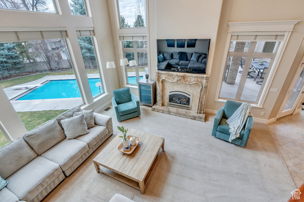 Living room with baseboards, a towering ceiling, a high end fireplace, and plenty of natural light