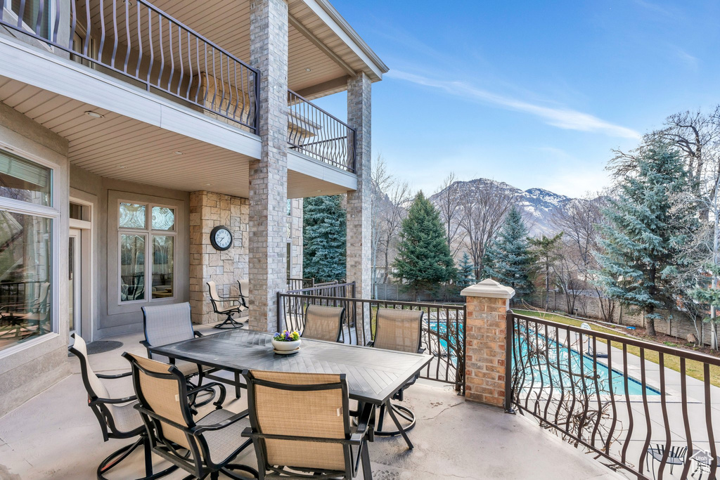 View of patio with a balcony, a mountain view, outdoor dining area, and a fenced in pool