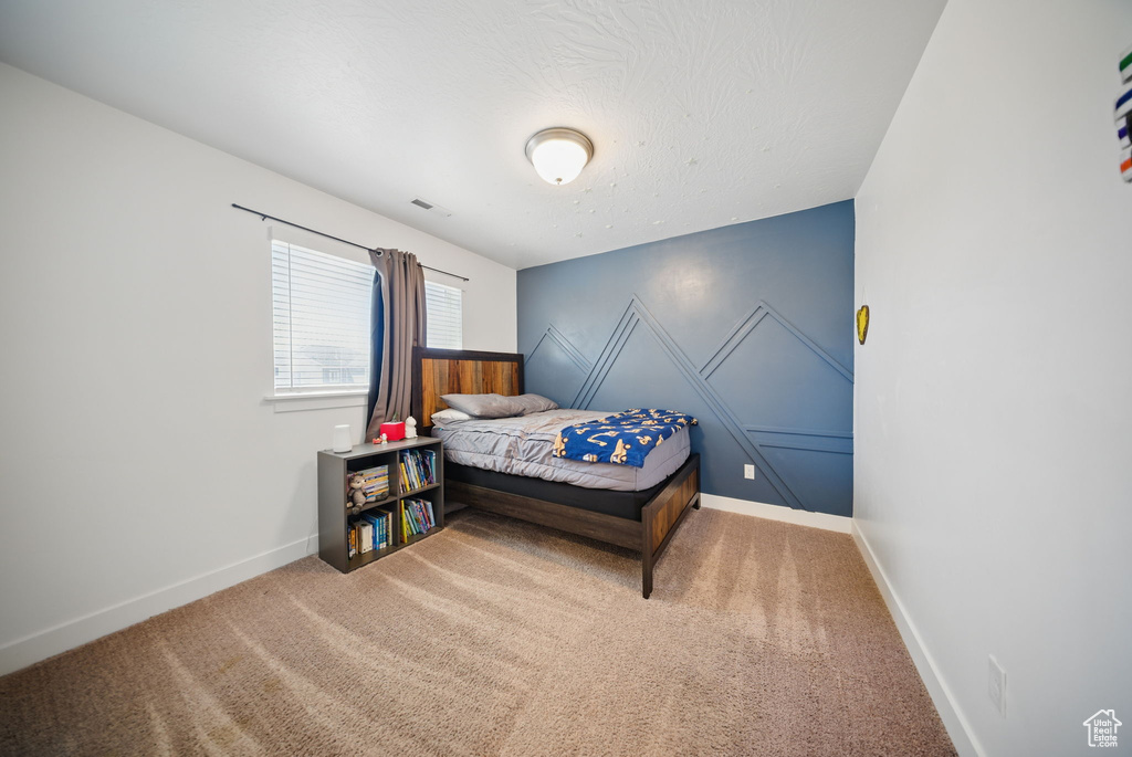 Carpeted bedroom featuring a textured ceiling, baseboards, and visible vents