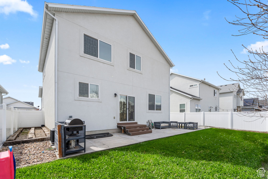 Rear view of house with a patio, stucco siding, a fenced backyard, and a yard