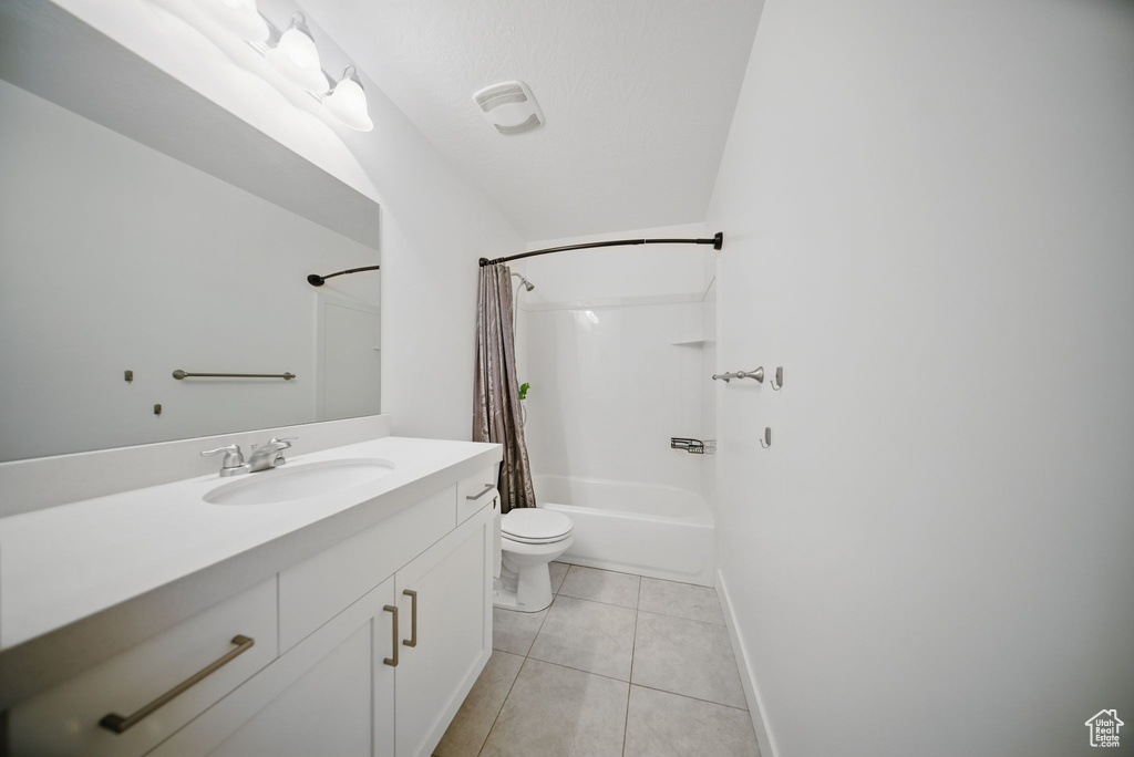 Full bath with shower / bath combo, baseboards, toilet, vanity, and tile patterned flooring