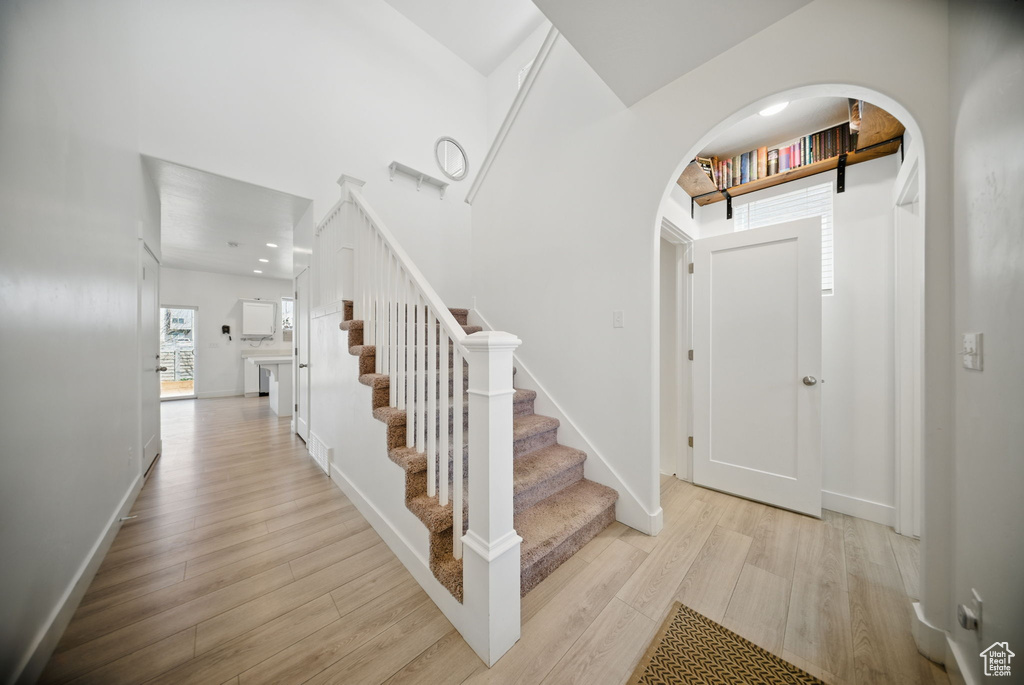 Foyer entrance featuring stairs, wood finished floors, baseboards, arched walkways, and recessed lighting