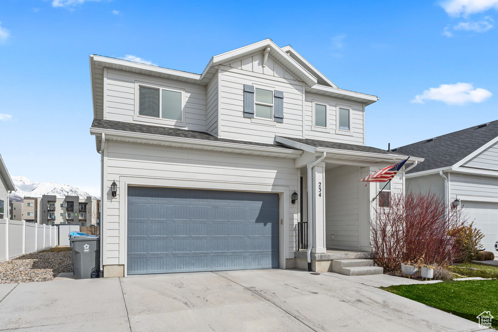 View of front facade with fence, a garage, board and batten siding, and concrete driveway