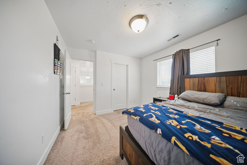 Bedroom featuring light carpet, baseboards, and visible vents