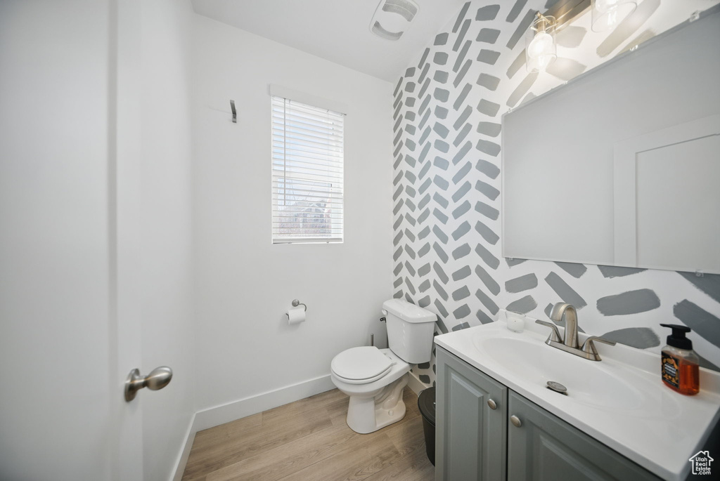 Bathroom with baseboards, toilet, vanity, and wood finished floors