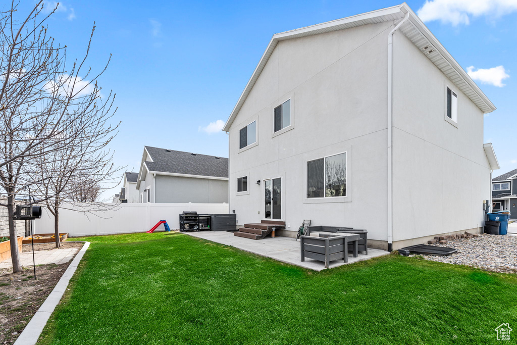 Rear view of house with entry steps, a patio, a lawn, a fenced backyard, and stucco siding