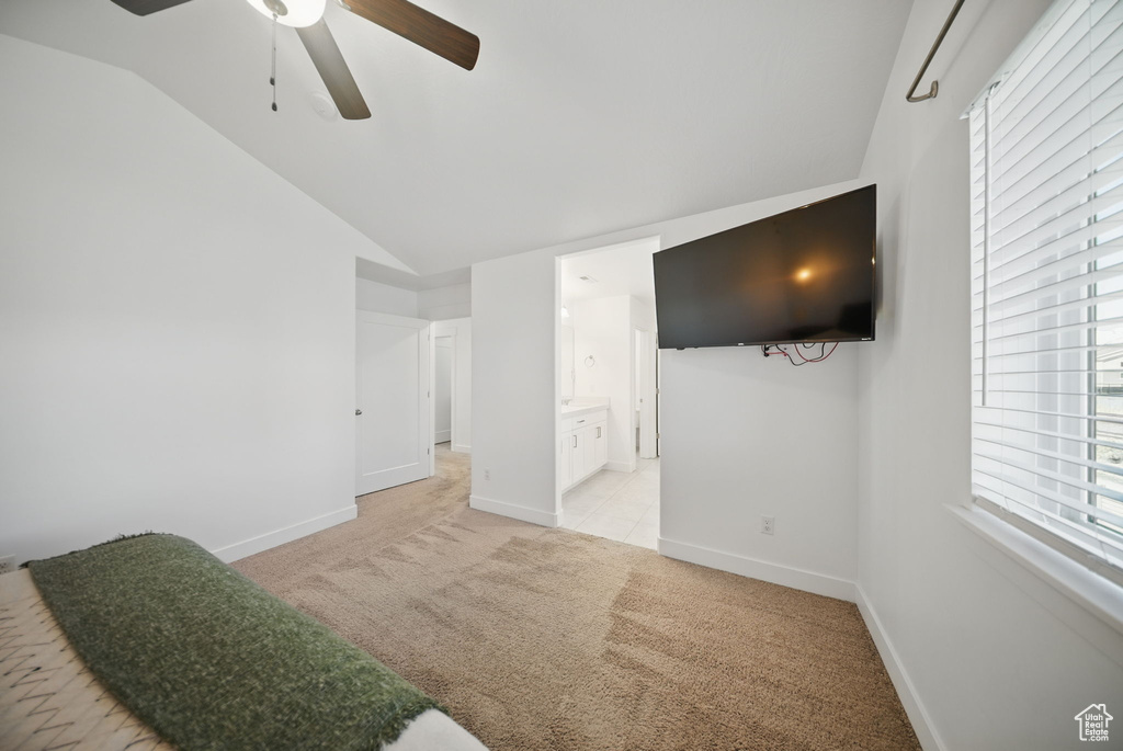 Bedroom featuring connected bathroom, a ceiling fan, lofted ceiling, baseboards, and light colored carpet