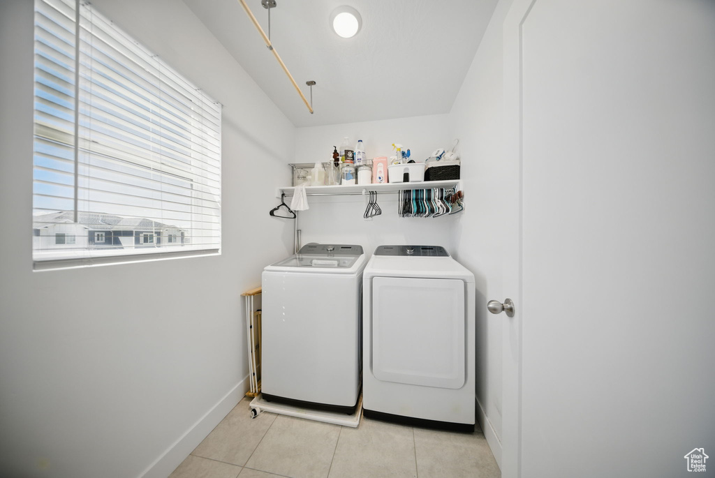 Clothes washing area featuring separate washer and dryer, light tile patterned flooring, baseboards, and laundry area
