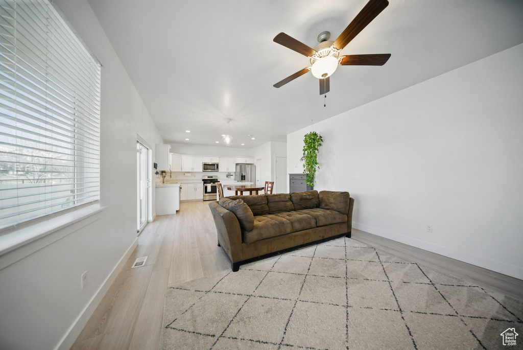 Living room featuring visible vents, baseboards, recessed lighting, a ceiling fan, and light wood-style floors