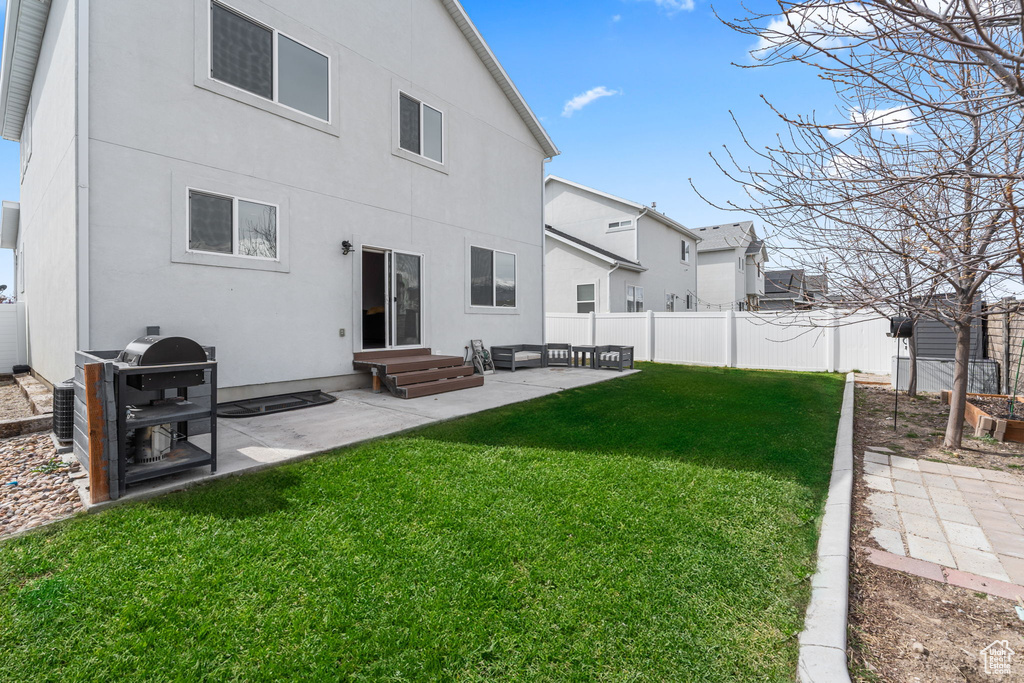 Back of house with a patio, a lawn, stucco siding, and entry steps