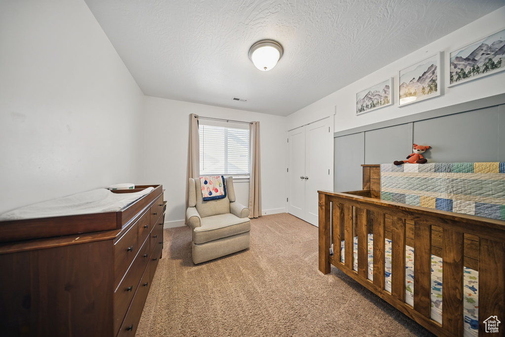 Bedroom featuring visible vents, baseboards, light colored carpet, and a textured ceiling