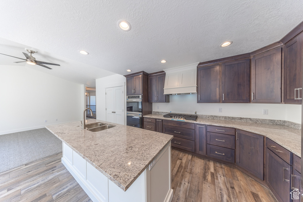 Kitchen featuring a sink, stainless steel appliances, a center island with sink, recessed lighting, and dark wood-type flooring