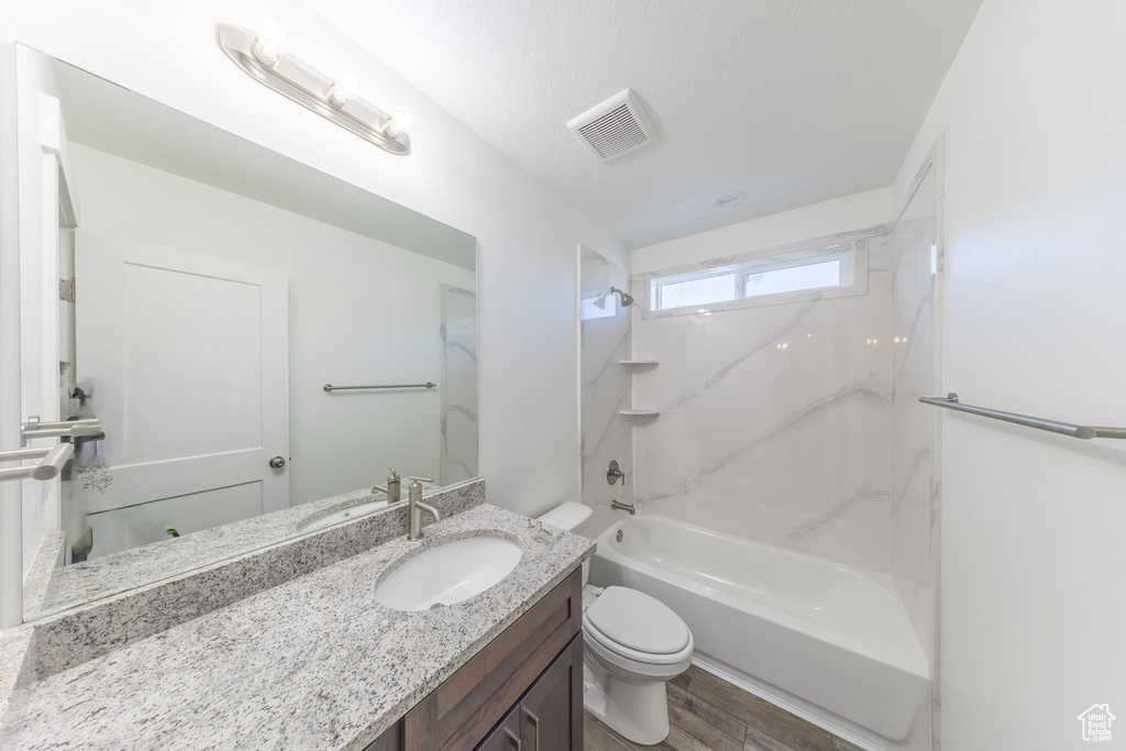 Full bath with toilet, vanity, wood finished floors, and shower / bath combination