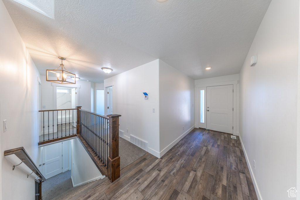Hallway with an upstairs landing, hardwood / wood-style floors, baseboards, a textured ceiling, and recessed lighting