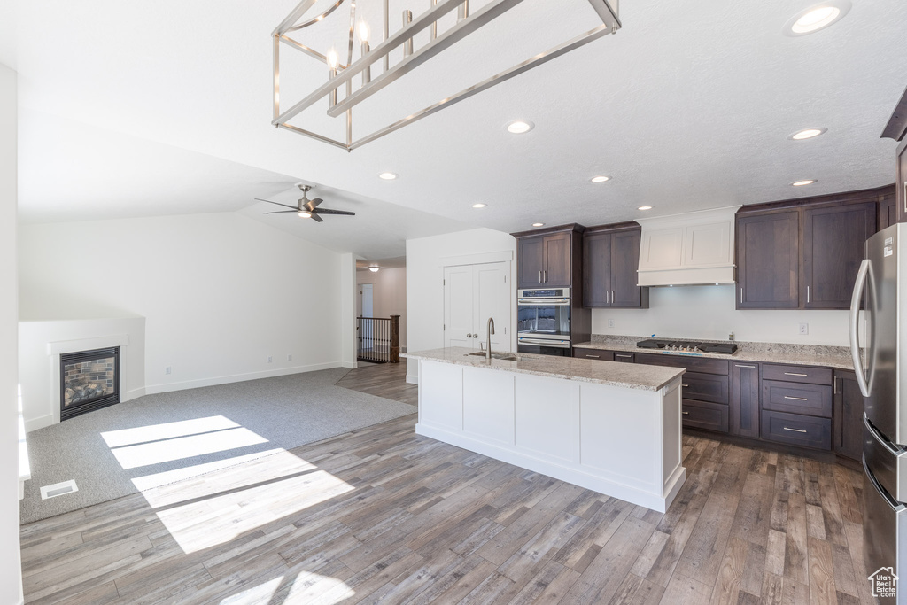 Kitchen featuring appliances with stainless steel finishes, a sink, recessed lighting, dark brown cabinets, and open floor plan