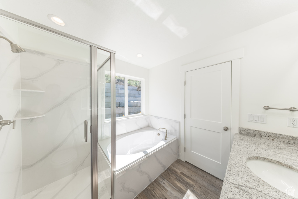 Full bathroom featuring a marble finish shower, a garden tub, vanity, wood finished floors, and recessed lighting