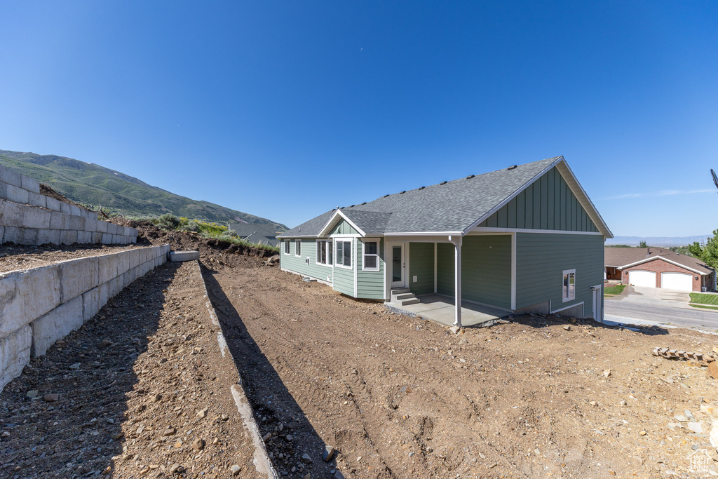 Rear view of house featuring board and batten siding and a shingled roof