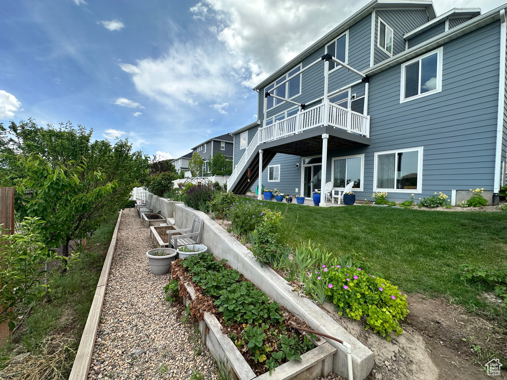 Back of property featuring a garden, a wooden deck, and a patio area