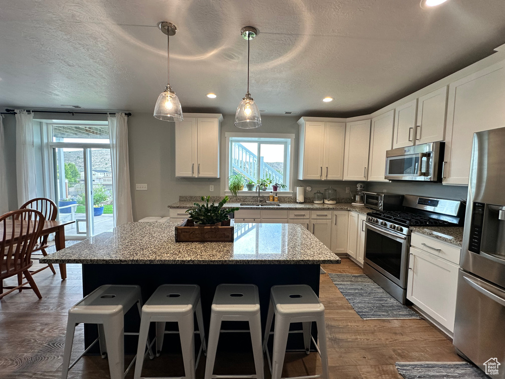 Kitchen with stainless steel appliances, a sink, a kitchen island, a kitchen bar, and recessed lighting