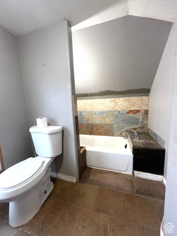 Bathroom featuring toilet, a bath, and baseboards