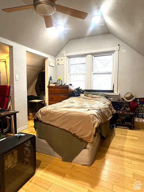 Bedroom with a closet, vaulted ceiling, a textured ceiling, and wood-type flooring