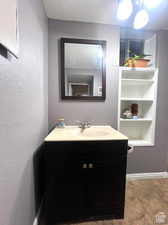 Bathroom featuring vanity, built in shelves, baseboards, and a textured ceiling