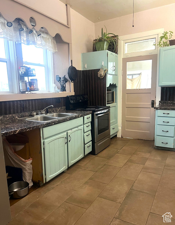 Kitchen with a sink, tile patterned floors, green cabinetry, and stainless steel range with electric cooktop