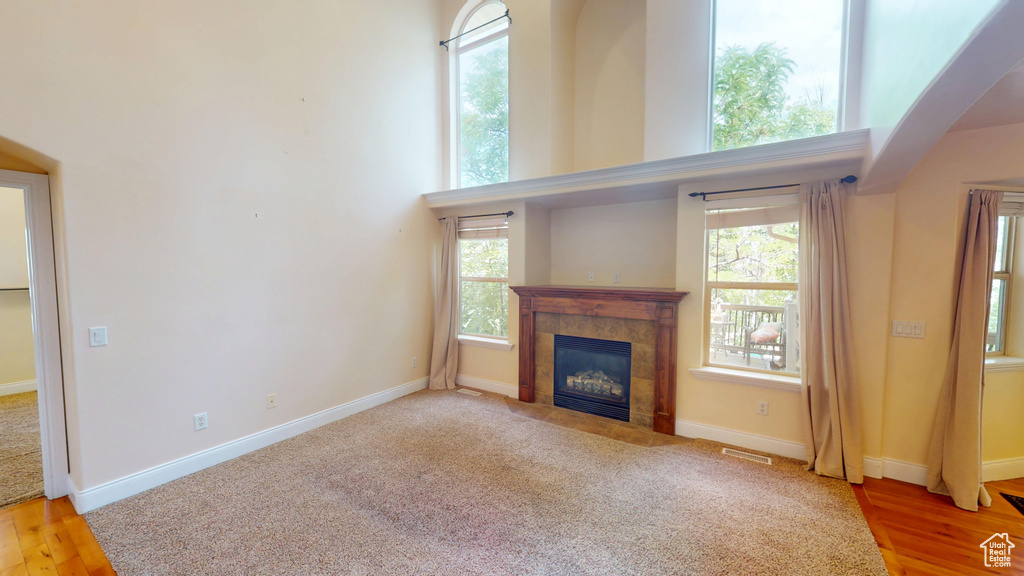 Unfurnished living room featuring healthy amount of natural light, a fireplace, and wood finished floors